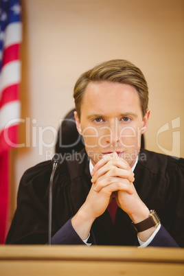 Unsmiling judge with american flag behind him