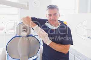 Smiling dentist leaning against dentists chair