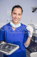 Smiling dentist holding tray and angle mirror