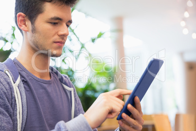 Young student using his tablet in cafe