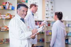 Smiling pharmacist in lab coat writing a prescription