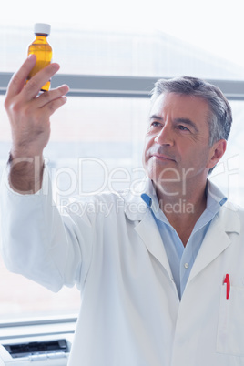 Smiling scientist in lab coat holding a chemical bottle