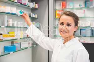 Junior pharmacist taking medicine from shelf