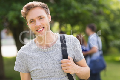 Handsome student smiling at camera outside on campus