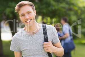 Handsome student smiling at camera outside on campus