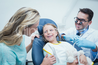 Dentist examining girls teeth with assistant