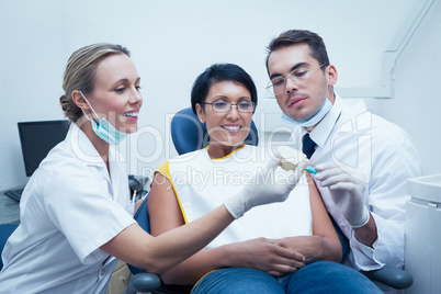 Dentists showing woman prosthesis teeth