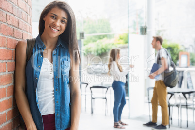 Pretty student smiling at camera with classmates behind