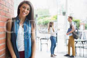 Pretty student smiling at camera with classmates behind