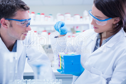 Two chemists wearing safety glasses and working together