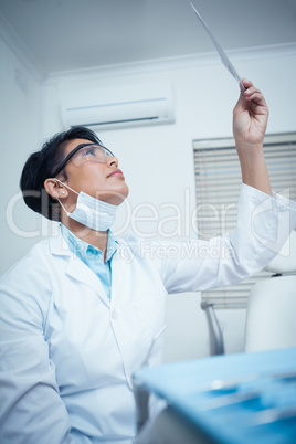 Concentrated young female dentist looking at x-ray