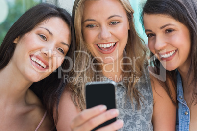 Happy students looking at smartphone outside on campus