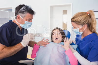 Scared young patient protesting about dentist and his nurse