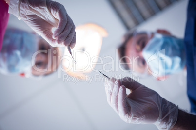 Dentist and assistant leaning over patient with tools