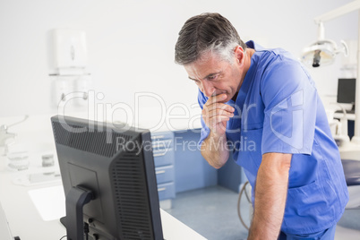 Thoughtful dentist using computer