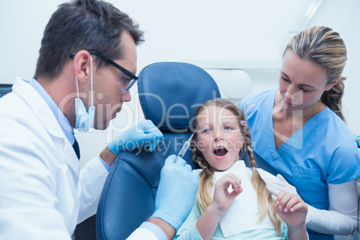 Dentist with assistant examining girls teeth