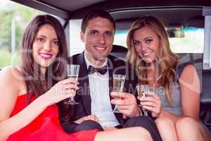 Happy friends drinking champagne in limousine