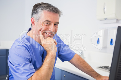 Portrait of a smiling dentist using computer