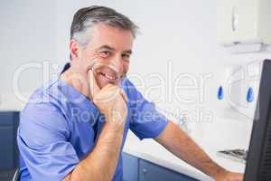 Portrait of a smiling dentist using computer