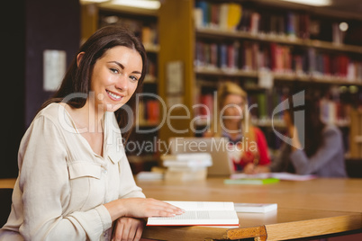 Smiling student sitting at desk reading text book