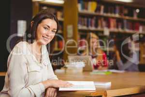 Smiling student sitting at desk reading text book