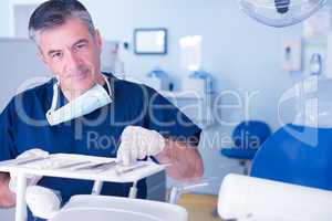 Dentist picking up tool and smiling at camera