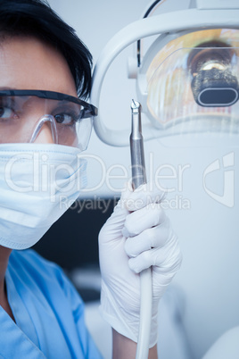 Dentist in surgical mask holding dental drill