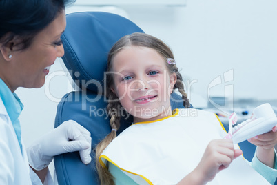 Female dentist teaching girl how to brush teeth