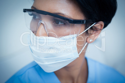 Female dentist wearing surgical mask and safety glasses