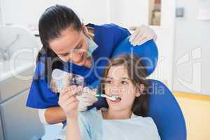 Pediatric dentist brushing teeth to her young patient