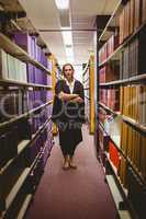 Stern lawyer standing between shelfs with arms crossed
