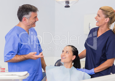 Smiling dentist and nurse speaking with their patient