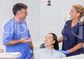 Smiling dentist and nurse speaking with their patient