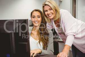 Smiling teacher and student behind desk at computer