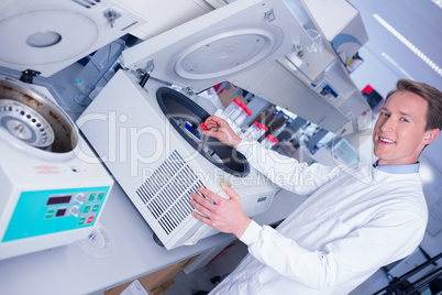 Smiling chemist using a centrifuge looking at camera