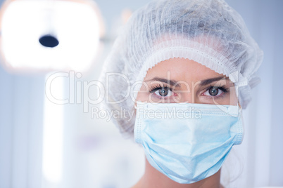 Dentist in surgical mask and cap looking at camera