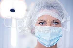 Dentist in surgical mask and cap looking at camera