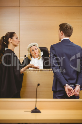 Judge and lawyer listening the criminal in handcuffs