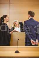 Judge and lawyer listening the criminal in handcuffs