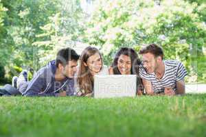 Happy students using laptop outside