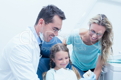 Happy male dentist with assistant and girl