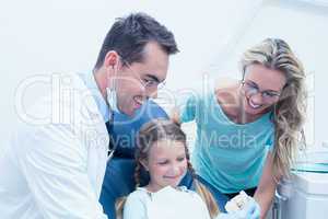 Happy male dentist with assistant and girl