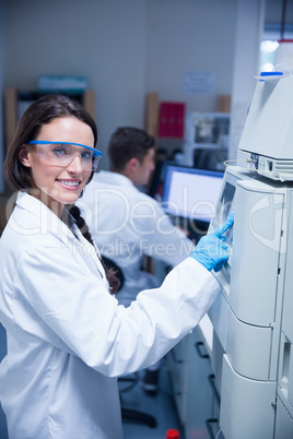 Smiling young chemist using the machine