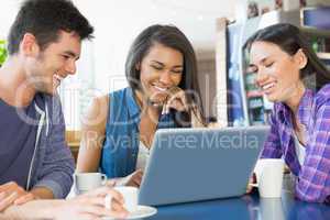 Young students doing assignment on laptop together