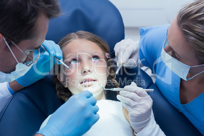 Dentist with assistant examining girls teeth