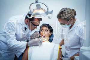 Dentist with assistant examining womans teeth