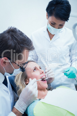 Male dentist with assistant examining womans teeth Male dentist with assistant examining womans teeth