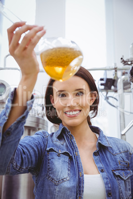 Woman looking at camera while holding beaker of beer