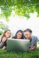 Happy students using laptop outside