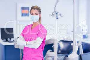 Dentist in pink scrubs looking at camera with arms crossed